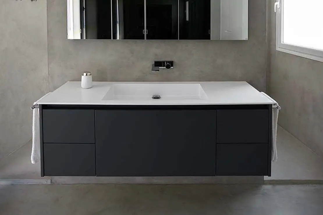 Baño de microcemento con pavimento, muros y ducha de tonalidad gris.